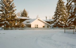 house-with-snowy-pine-trees-winter-beginning-to-melt-and-experience-spring-thaw-and protecting-your-home-from-water-damage